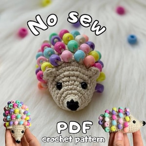 May include: A crocheted hedgehog with colorful bead accents. The beige hedgehog has black eyes and a black nose. The image includes the text "No sew" and "PDF crochet pattern".
