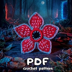 May include: A red and white crocheted Demogorgon flower with a black center and blue trim. The image includes the text "PDF crochet pattern". The background features a forest scene with a full moon.