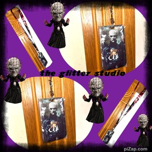 May include: A lanyard and a keychain featuring a horror movie character. The lanyard has a black and red design. The keychain has a picture of the character. The text "the glitter studio" is visible.