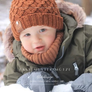 May include: A close-up of a baby wearing a brown knitted hat and matching scarf. The hat has a cable knit pattern and a leather label with a bear logo. The text "EASY MUSTER MÜTZE" and "BlüdalDesign" is visible on the image. The text "WOLLE: LANG YARNS MERINO 120" is also visible.