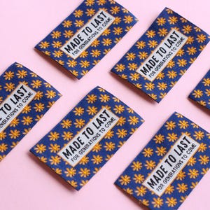 May include: Five blue fabric labels with a yellow flower pattern and white text that reads "MADE TO LAST FOR GENERATIONS TO COME".