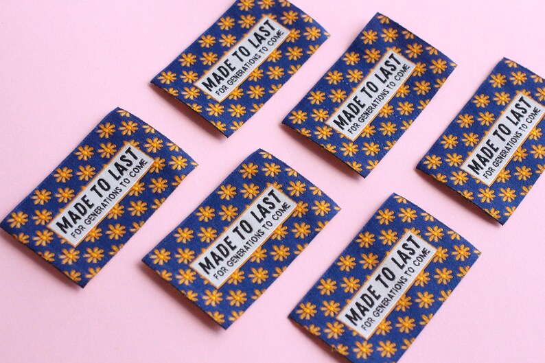May include: Five blue fabric labels with a yellow flower pattern and white text that reads "MADE TO LAST FOR GENERATIONS TO COME".