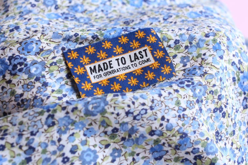 May include: A blue fabric with a white floral pattern. A blue and yellow label with the text "Made to Last for Generations to Come" is attached to the fabric.