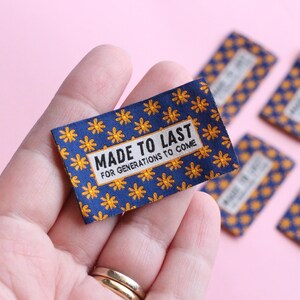 May include: A close-up of a blue fabric label with a yellow flower pattern. The label reads "Made to Last for Generations to Come".
