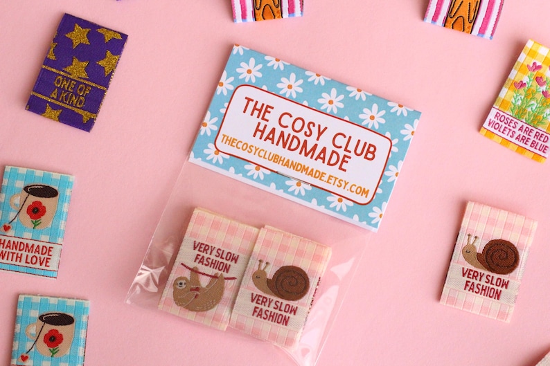Peut inclure: Un ensemble de quatre &eacute;tiquettes en tissu thermocollantes &agrave; motif vichy rose et blanc. Les &eacute;tiquettes pr&eacute;sentent un paresseux, un escargot, une tasse de th&eacute; et un motif de marguerite. Les &eacute;tiquettes sont emball&eacute;es dans un sac en plastique transparent avec une carte bleue et blanche qui indique "The Cosy Club Handmade" et "thecosyclubhandmade.etsy.com".