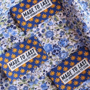 May include: Three blue fabric labels with white and yellow stars and the text "MADE TO LAST FOR GENERATIONS TO COME" on a white background with a blue floral pattern.