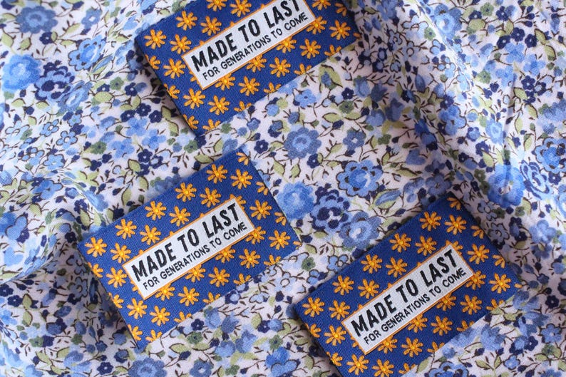 May include: Three blue fabric labels with white and yellow stars and the text "MADE TO LAST FOR GENERATIONS TO COME" on a white background with a blue floral pattern.