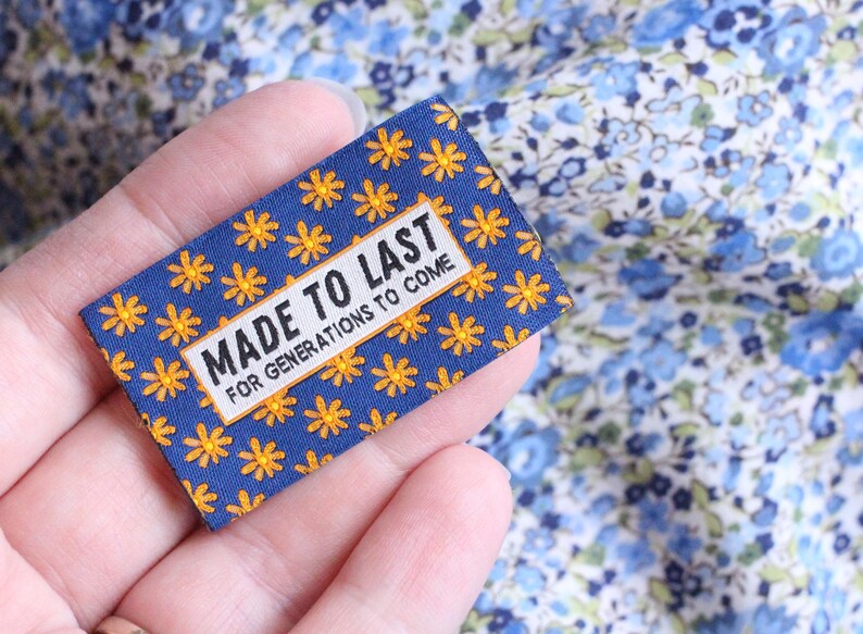 May include: A blue fabric label with a yellow daisy pattern and the text "MADE TO LAST FOR GENERATIONS TO COME".