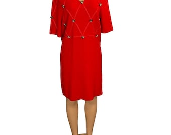 May include: A red dress with a diamond pattern and gold-toned buttons. The dress has short sleeves and a v-neck.