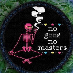 Pode incluir: Um esqueleto pixelado preto e rosa usando óculos de sol e fumando um baseado, sentado em uma pose meditativa. O texto "no gods no masters" está escrito em branco sobre um fundo preto. A imagem é cercada por uma moldura preta com uma borda azul.
