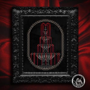 Puede incluir: Obra de arte de punto de cruz enmarcada en negro con un dise&ntilde;o de fuente g&oacute;tica. La fuente est&aacute; representada en tonos grises y rojos sobre un fondo negro, enmarcada por un borde ovalado decorativo. El marco es negro con detalles ornamentados.