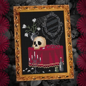 May include: A framed cross-stitch embroidery depicting a skull, a vase of white flowers, a mirror, and a bottle on a red table with candlesticks. The background is black with a spiderweb.