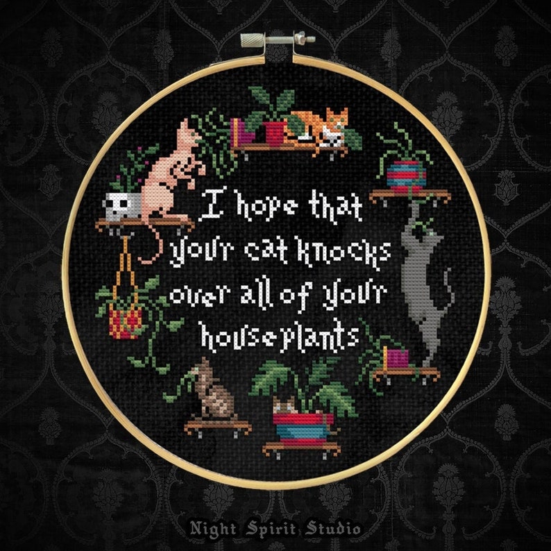 May include: Black and white embroidery hoop with the text "I hope that your cat knocks over all of your houseplants". The embroidery features a variety of houseplants, cats, and a hanging planter.
