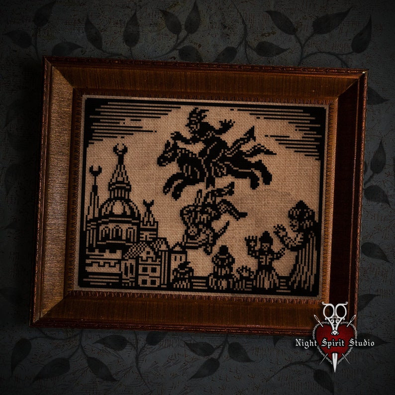 May include: A framed cross-stitch embroidery depicting a black silhouette of a witch riding a horse over a city skyline. The embroidery is on a beige fabric and the frame is brown wood.