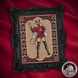 May include: A cross stitch pattern of a devil figure in a red and black costume, holding a trident. The figure is standing on a beige background with a black border. The pattern is framed in a black ornate frame.