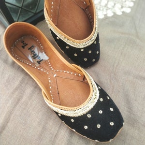 May include: Pair of black velvet flat shoes with gold trim and small gold dots. The shoes have a brown leather insole and the label "Talwar Inc." is visible on the inside of one shoe.