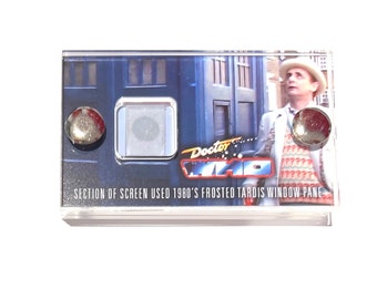 May include: A clear acrylic frame with a section of screen used in the 1980s Doctor Who series. The frame features a frosted TARDIS window pane with a picture of the Doctor in a white jacket and a red and white sweater. The text "Doctor Who" is printed on the frame.