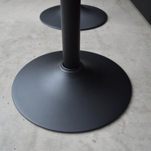 May include: Black metal table base with a wide, round, flat base.