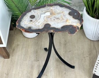 May include: A round agate table top with brown and white patterns sits on a black metal tripod stand.