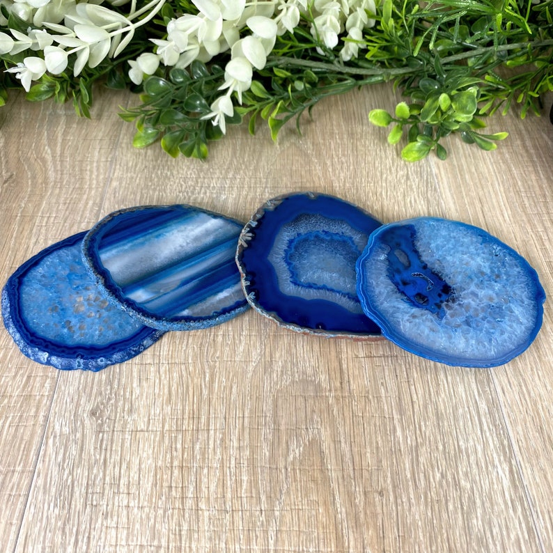 May include: Four blue agate coasters with different patterns. The coasters are round and have a natural, polished finish.