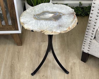 May include: A small side table with a natural agate stone top. The stone is white and gray with a central pattern. The table has a black metal base with three legs. The table is approximately 18 inches in diameter.