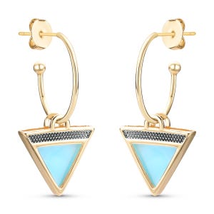 Pode incluir: Brincos de argola dourados com um pingente triangular que apresenta uma pedra azul claro e detalhes pretos.