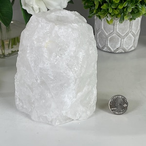 May include: A white, natural crystal candle holder shaped like a rock with a smooth, round top. The holder is about 4 inches tall and 3 inches wide.