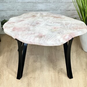 May include: A white and pink irregular shaped coffee table with a black metal base. The table has a natural, organic look.