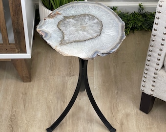 May include: A white agate slice end table with a black metal base. The table has a natural, organic shape and a polished finish.