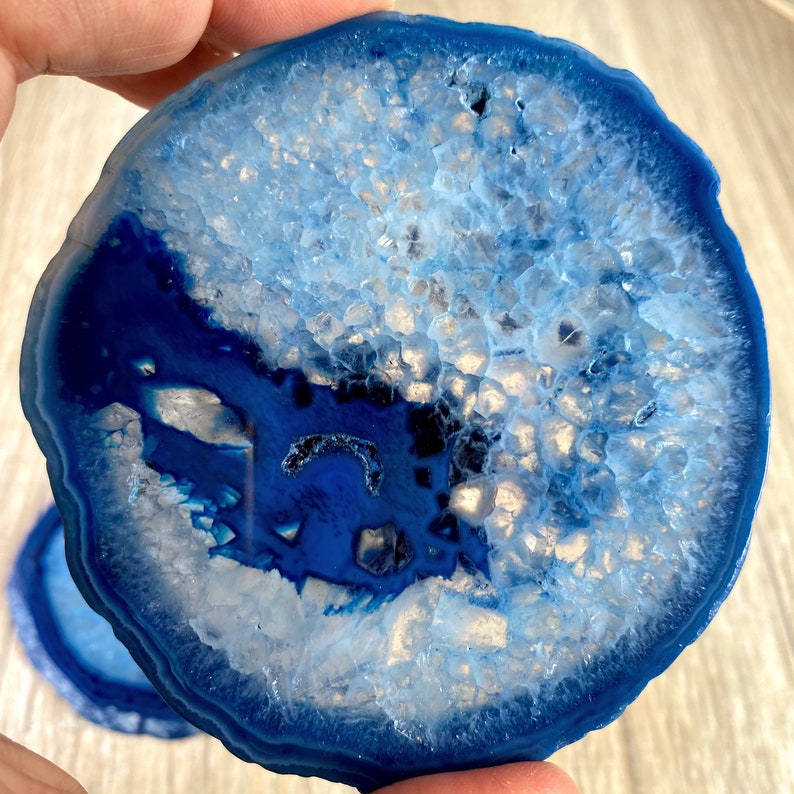 May include: A blue agate coaster with a white and blue crystal pattern. The coaster is round and has a smooth, polished surface.