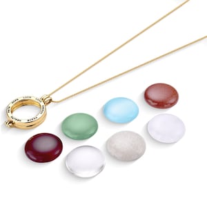 May include: A gold necklace with a round pendant that has the words "Peace, Health, Hope, Faith, Love, Energy, Luck" inscribed around the edge. The pendant is open and can be used to hold a small stone or charm. There are seven different colored stones in the image, including red, green, blue, white, and brown.