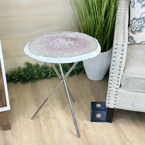 May include: A small, round side table with a natural agate stone top in shades of lavender and white. The table has a silver metal, tripod-style base. The table is approximately 46 cm in diameter and 51 cm tall.