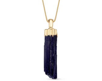 May include: A gold chain necklace with a dark blue, raw, crystal pendant.