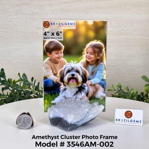 May include: A clear photo frame with a picture of two children and a dog, resting on a large amethyst cluster. The frame is 4" x 6" (approx. 10cm x 15cm). The frame is labeled "BRAZILGEMS". The product is an Amethyst Cluster Photo Frame, Model # 3546AM-002.