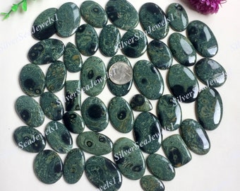 May include: A collection of polished, oval-shaped gemstones in shades of dark green and black. The stones vary in size and have unique patterns. The image includes a US quarter for size reference. The text "SilverSeaJewels1" is visible in the image.