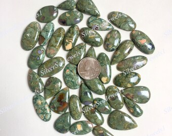 May include: A collection of polished gemstones in various shapes, including ovals and teardrops. The stones feature a mottled pattern of green, brown, and cream colors. A US quarter is included for size reference. The gemstones are likely for jewelry making.