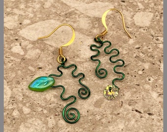 May include: A pair of green wire earrings with a leaf-shaped charm on one earring and a clear crystal charm on the other.