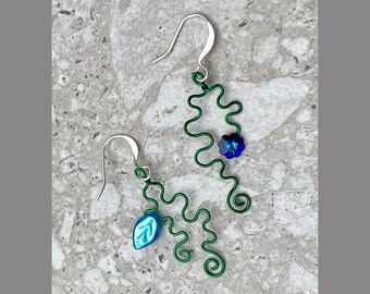 May include: A pair of green wire earrings with blue and turquoise glass beads. The earrings are shaped like a vine with leaves and flowers.