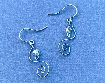 May include: A pair of silver earrings with a crystal bead dangling from each earring. The earrings are made of wire that is twisted into a spiral shape.
