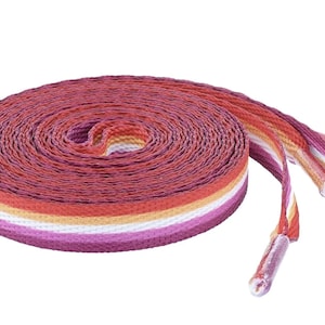 May include: A pair of shoelaces with a pink, white, orange, and red striped pattern. The shoelaces are coiled up and the ends are visible.