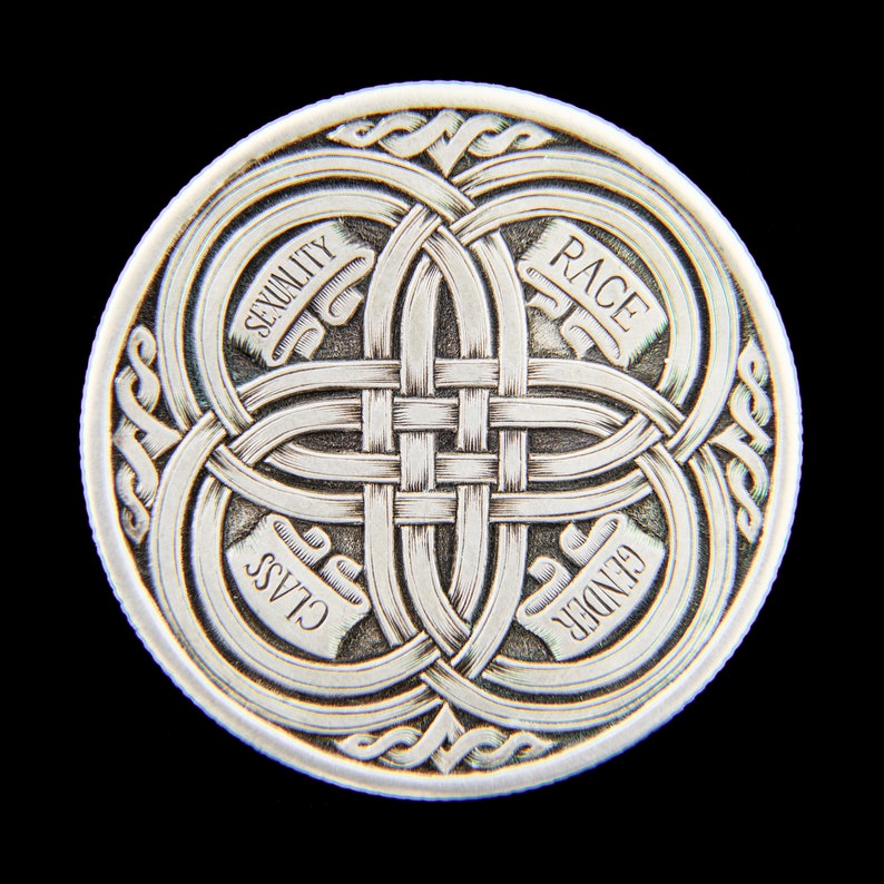 May include: A silver coin with a Celtic knot design and the words "Race", "Gender", "Class", and "Sexuality" inscribed around the edges.