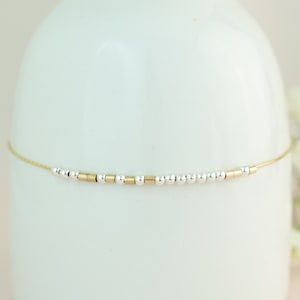 May include: A delicate gold chain bracelet with alternating silver and gold beads.