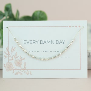 May include: A silver beaded bracelet with the text "EVERY DAMN DAY" on a white card with a floral design.