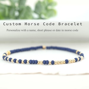 May include: A custom Morse code bracelet with navy blue beads and gold accents. The bracelet is personalized with a name, short phrase, or date in Morse code. The text "Custom Morse Code Bracelet" is visible.