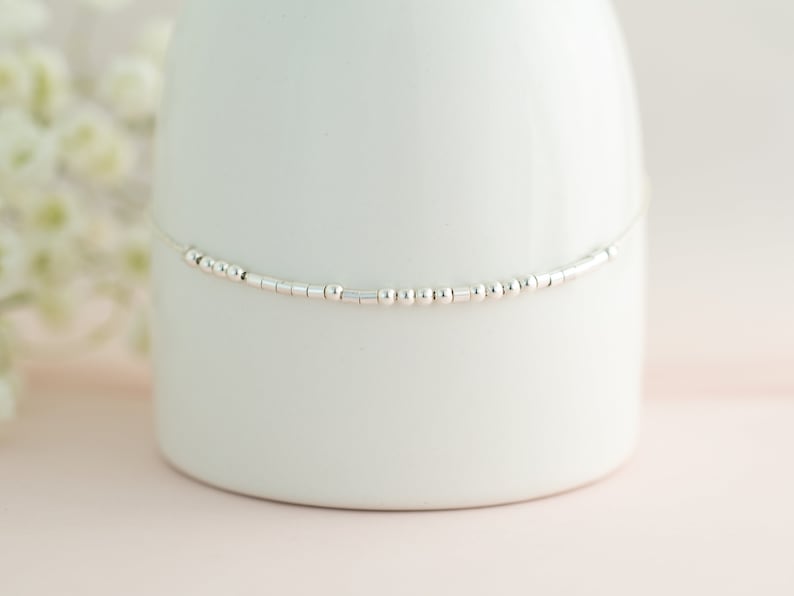 May include: A delicate silver chain anklet with small round and rectangular beads.