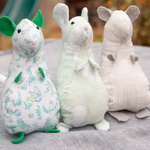 May include: Three handmade plush mouse toys. One mouse is green and white with a floral pattern, one is white with a green floral pattern, and one is white with a grey floral pattern.