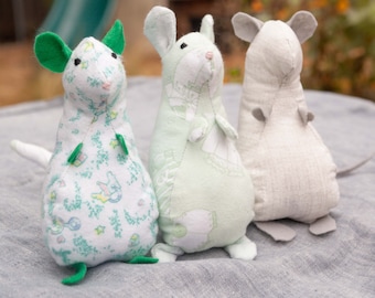 May include: Three handmade plush mice toys. One mouse is green and white with a floral pattern, one is white with a green floral pattern, and one is white with a gray floral pattern.
