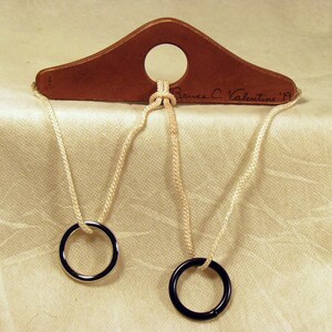 May include: A wooden puzzle with two rings and a piece of string. The string is threaded through the rings and the wooden piece. The wooden piece has the inscription "Bruce C. Valentine '19".
