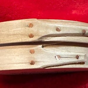 May include: A wooden oval box with a hinged lid. The box is made of light wood and has a natural finish. The lid is secured with small copper tacks.