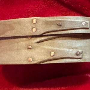 May include: A light brown wooden box with a hinged lid. The box is decorated with metal studs and has a rustic, vintage look.